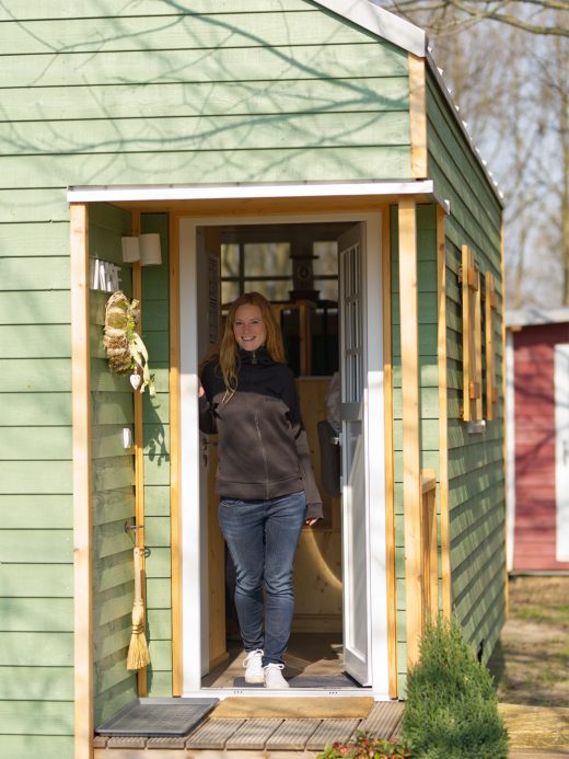 Das Foto zeigt Rebecca im Eingang eines grünen Tiny Houses des Pier 9 in Hamm