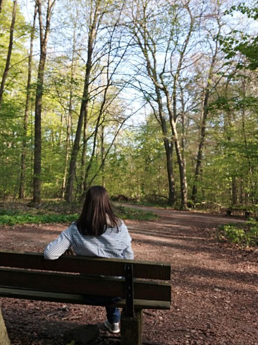 Das Foto zeigt Laura auf einer Bank im Wald in Duisburg beim Spazieren im Ruhrebiet