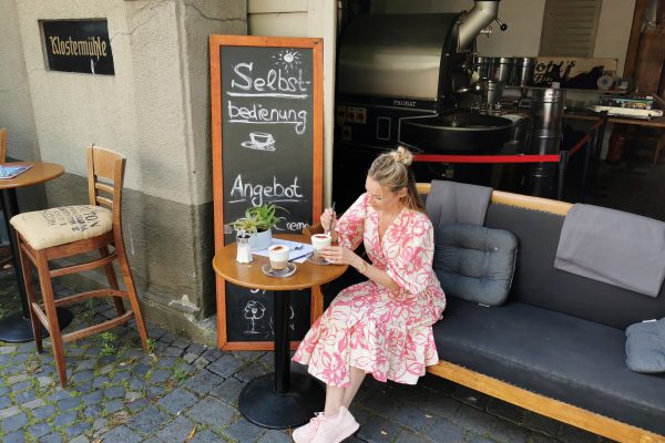 Das Bild zeigt Sandra mit einem Cappucino Freddo vor der Kaffeemanufaktur Pohl's Mühle in Hamm
