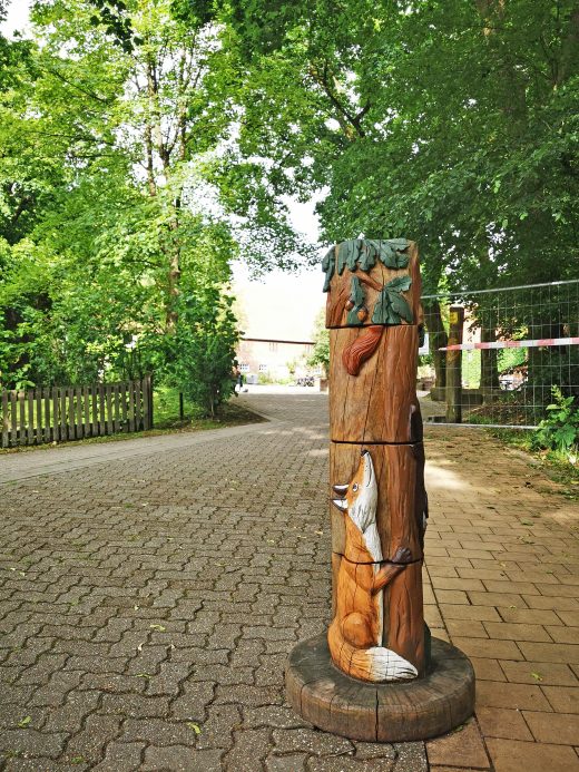 Das Foto zeigt Holzfiguren am Eingang des Heidhofs in Bottrop